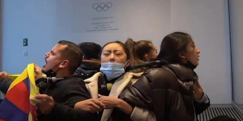 Tibetan students protest Beijing 2022 by chaining themselves to the Olympic insignia in front of the IOC.